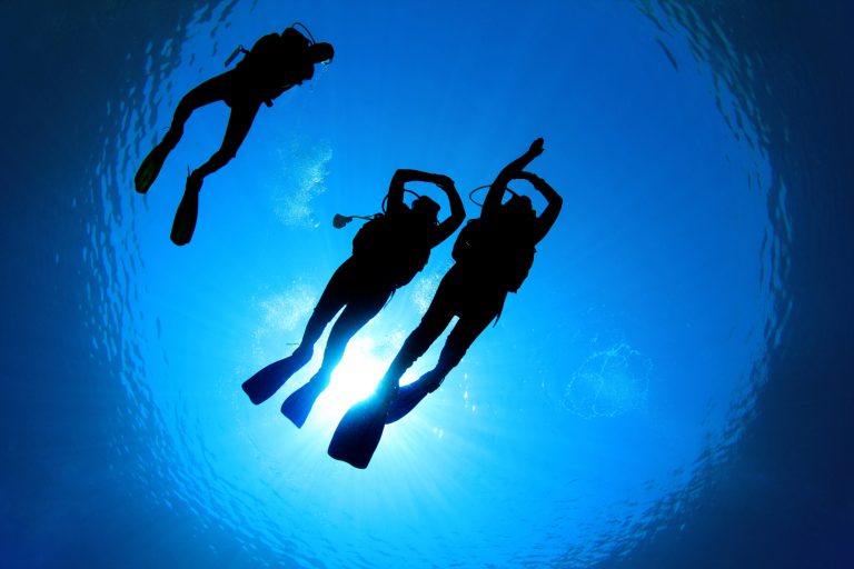 Three scuba divers practice underwater navigation.